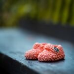 pair of baby's pink knit shoes on bench